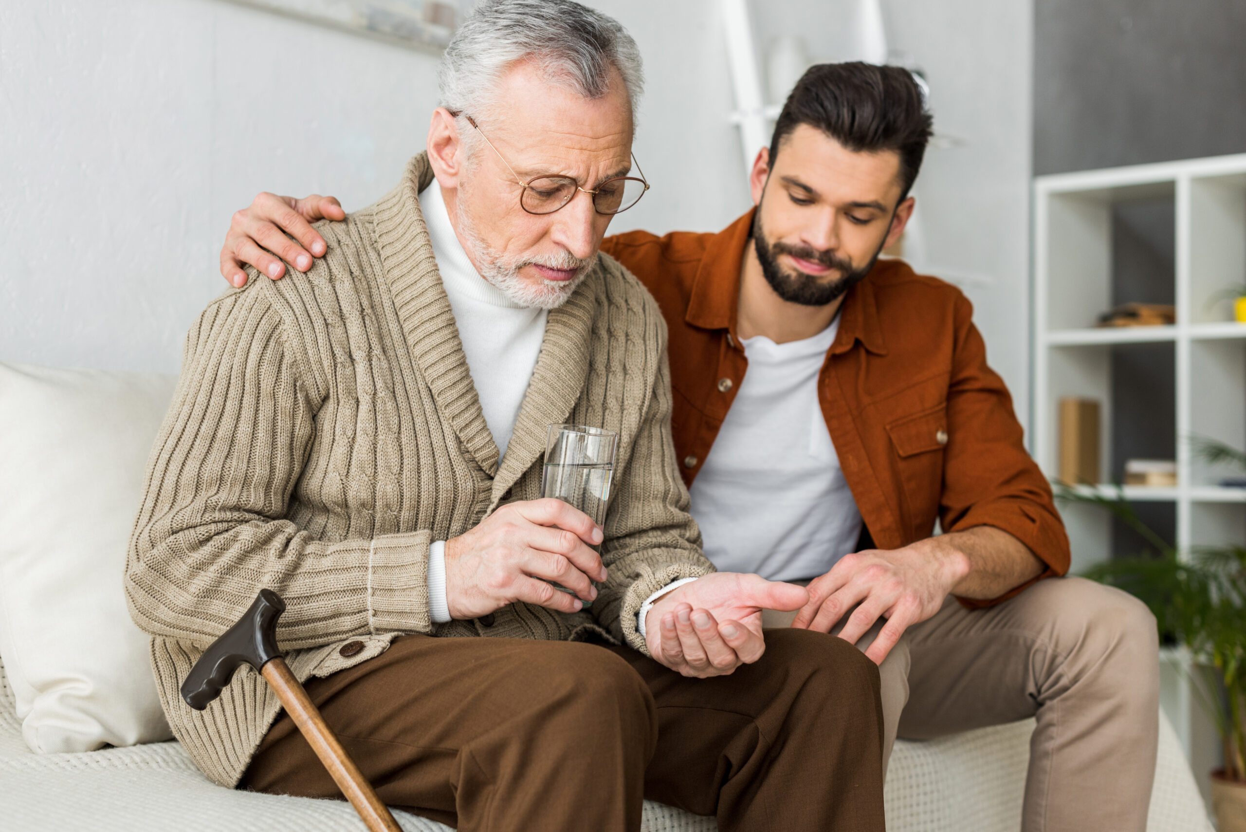 Caregiver supporting senior man with medication at home
